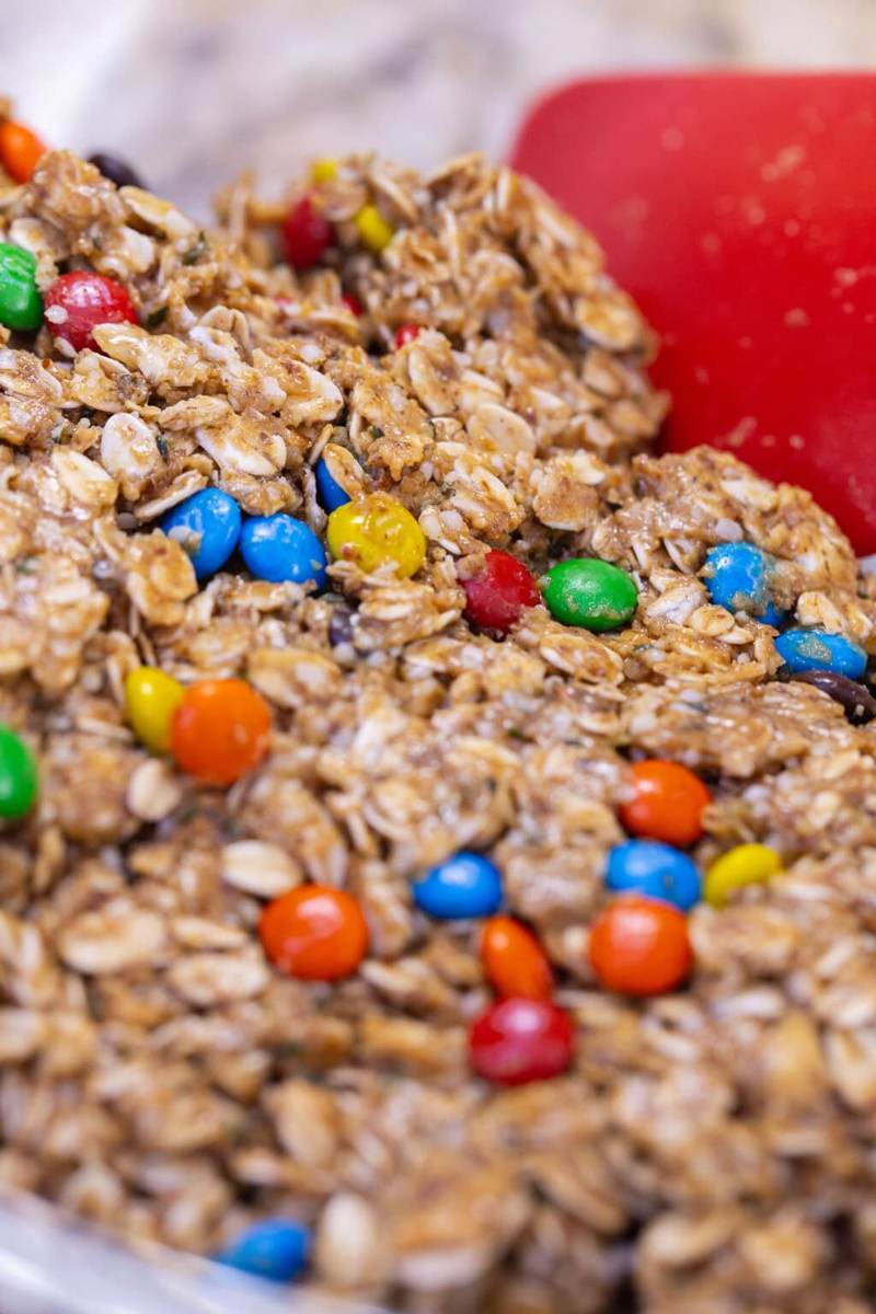 A spatula mixing the protein ball mixture in a large glass bowl.