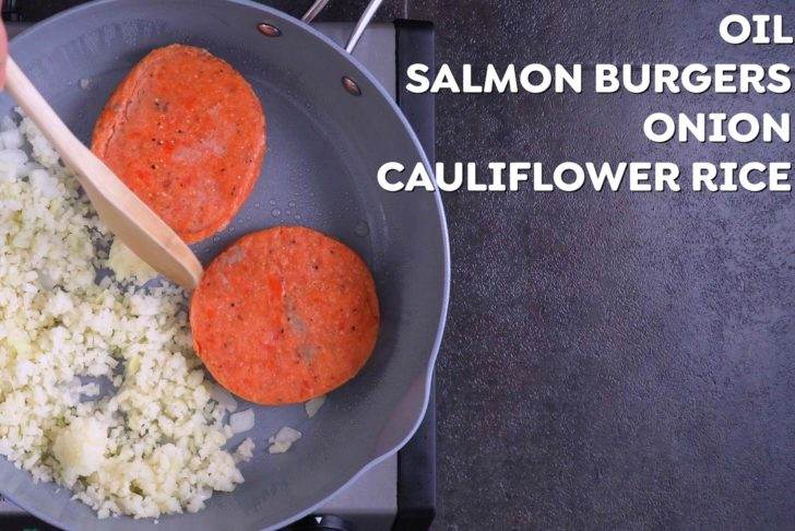Cook frozen salmon burgers on one side of a large pan, and cook onion and cauliflower rice on the other side.