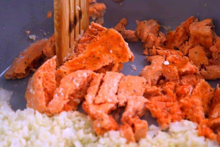 After 5 minutes, flip salmon burgers and break them up with a wooden spoon. Continue cooking another 5 minutes.