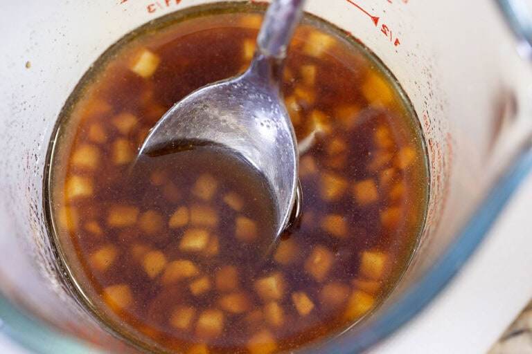 A spoon in a measuring cup, mixing together the sesame ginger marinade.