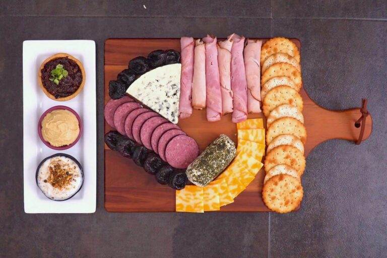 Arrange sliced cheeses & crackers around the larger items on the board.