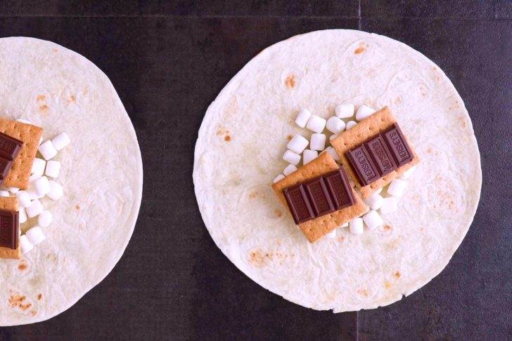 Layer marshmallows, graham crackers, and chocolate pieces onto center of tortilla.