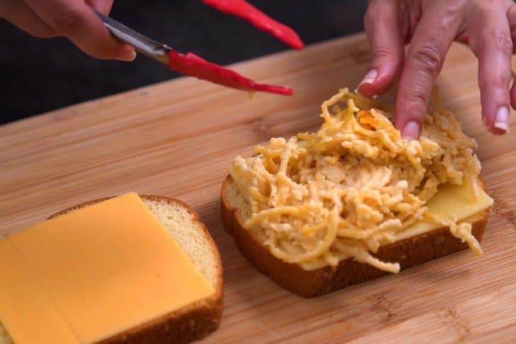 Layer cheese slices onto bread, followed by leftover spaghetti dish.