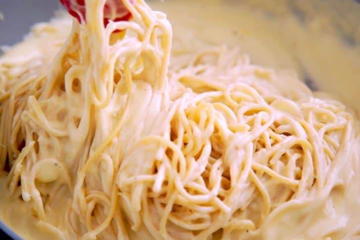 Add cooked spaghetti noodles into cheese sauce and toss to coat.