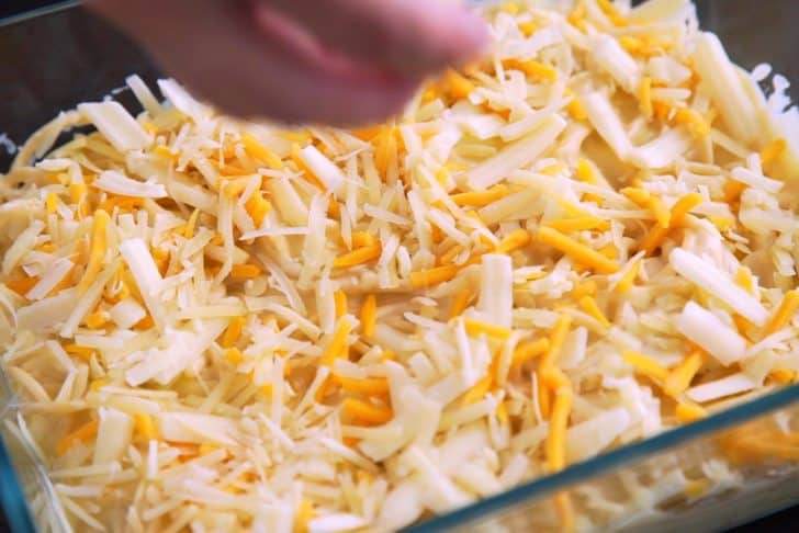 Transfer cheesy spaghetti to a casserole dish, cover with additional shredded cheese, and bake for 22-25 minutes.