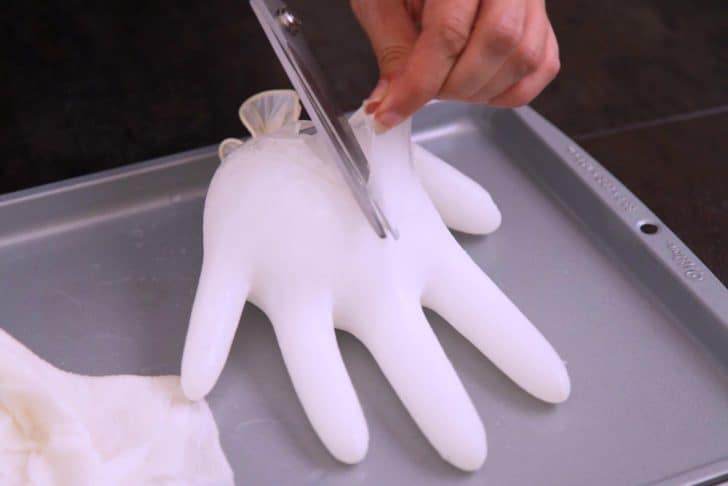 Once frozen, wipe outside of glove with a warm, wet paper towel to help loosen the ice from the glove. Cut the knot at the top, then cut away the rest of the glove to separate it from the ice.
