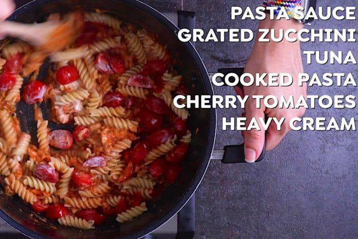 Add cooked pasta into sauce along with cherry tomatoes and a splash of cream, stirring to integrate.