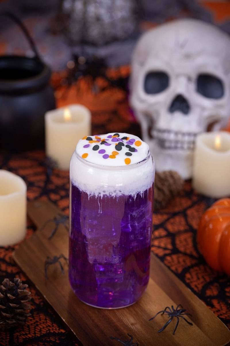 A halloween themed witch's brew dirty soda on a table with halloween decorations